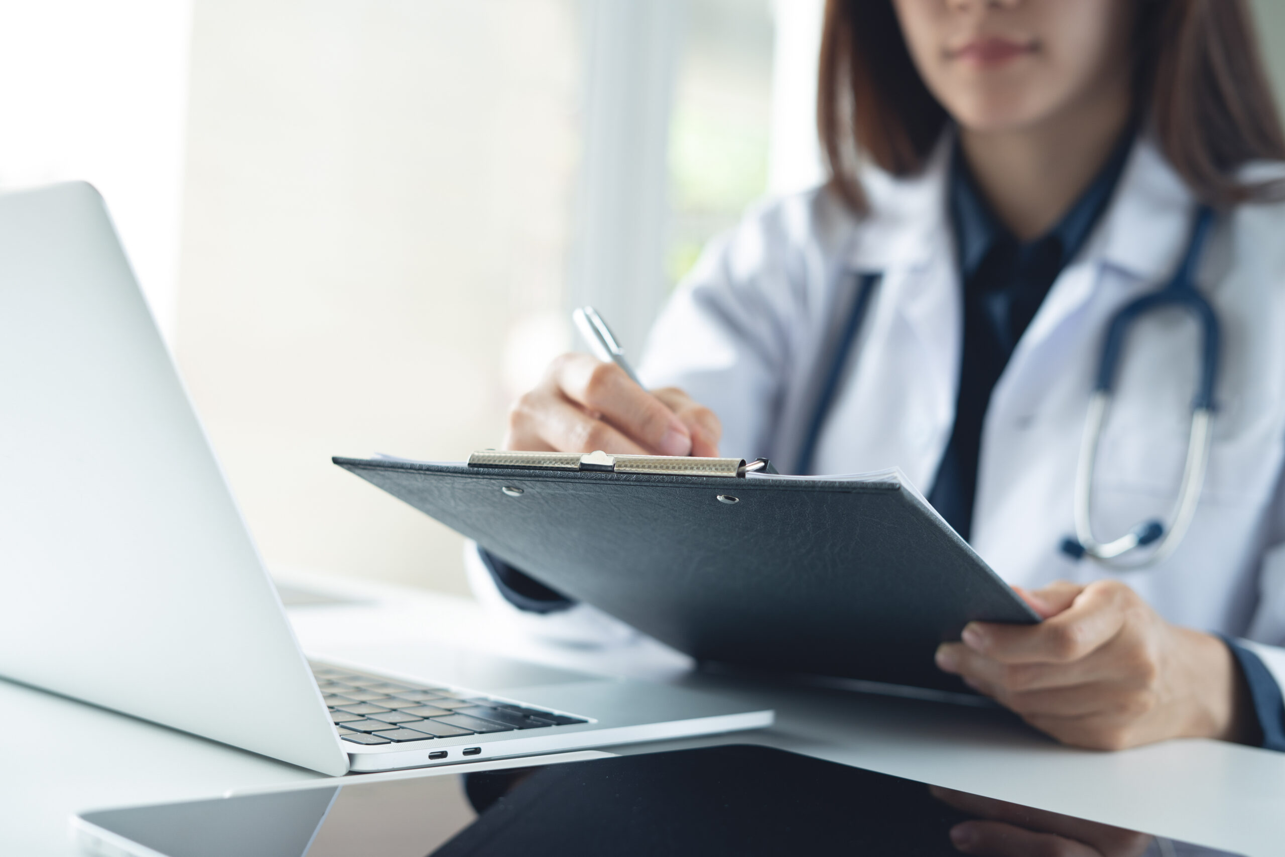 Asian femal doctor writing notes on clipboard for hospital schedule history record or healthcare checklist Doctor writing prescription medication document for patient in hospital office